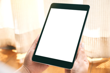 Mockup image of a woman holding black tablet pc with blank white desktop screen while laying down on the floor with feeling relaxed