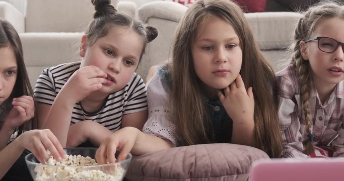 Siblings lying down watching movie and eating popcorn