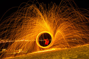 Large round burning fireworks sparkle from the burning steel wool. The city lights at night.