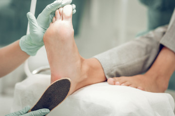 Accurate skilled beauty master wearing green gloves