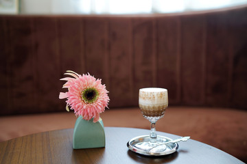 Iced mocha - A glass of coffee latte mixed with cocoa and topped with milk foam on wooden table and blurred background, Perfect for breakfast time.