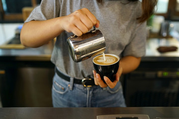 Barista making coffee with latte art, Created by pouring steamed milk into a shot of espresso and resulting in a pattern or design on the surface of the latte.