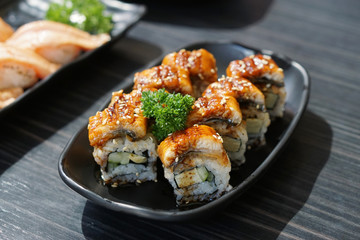 Unagi sushi roll - A plate of steamed rice topped with grilled freshwater eel and sweet sauce on wooden table, Traditional Japanese Food.