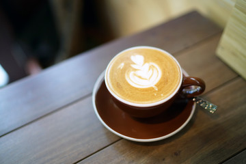 Hot flat white - A cup of coffee with milk and latte art on wooden table background and copy space, Perfect for breakfast time.