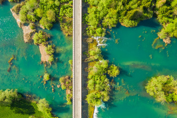 Croatia, road bridge over Mreznica river in Belavici village from drone, overhead shot countryside landscape view of waterfalls and trees in spring
