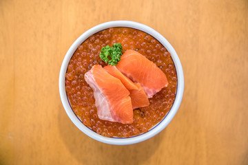 A bowl of salmon ikura don top view in table background