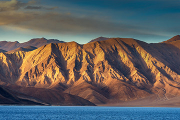 Fototapeta na wymiar Mountains and Pangong tso (Lake). It is huge and highest lake in Ladakh and blue sky in background, it extends from India to Tibet. Leh, Ladakh, Jammu and Kashmir, India