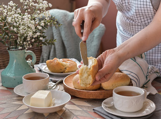 Homemade burger buns with basil in a woman's hand and butter. Served Table for breakfast and tea. Lifestyle photo