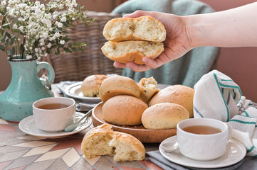 Homemade burger buns with basil in a woman's hand. Served Table for breakfast and tea. Lifestyle photo