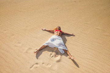 Beautiful caucasian woman enjoying summer holiday vacation travel lay down at the beach on the sand dunes having a sunbath - freedom and happiness lifestyle people outdoor in the nature