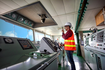duty officer in charge handle of the ship navigating to the port destination, navigation on the bridge of the ship vessel under voyage sailing to the sea - obrazy, fototapety, plakaty