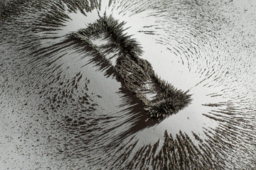 Iron dust showing the magnetic field near a magnet bar on white background