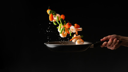 Sea food cooking shrimp with vegetables, on a dark background