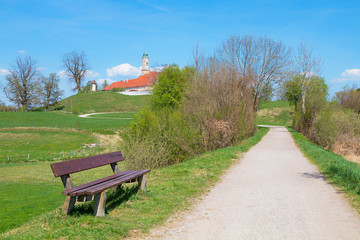 Idyllische Landschaft Kloster Reutberg in Oberbayern, mit Rastbank am Weg