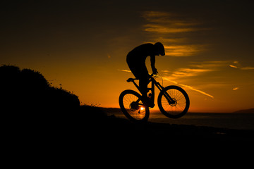 silhouette of cyclist on background of sunset sky