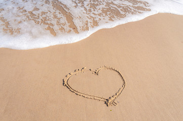 Fototapeta na wymiar Heart drawing on the sea wet sand