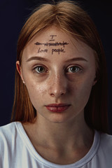 Portrait of young woman with mental health problems. The image of a tattoo on the forehead with the...