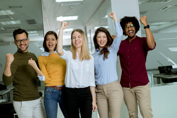 Group of young excited business people with hands up  standing in office