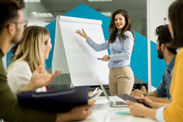 Confident young team leader giving a presentation to a group of young colleagues as they sit...