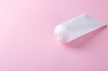 White plastic tube with cosmetic cream on the pink background.Cosmetic package for cream, empty space for the design