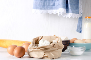 Fototapeta na wymiar Closeup of paper bagfull of flour, eggs and salt- key ingredients for dough.Rural mood, grandmother's kitchen