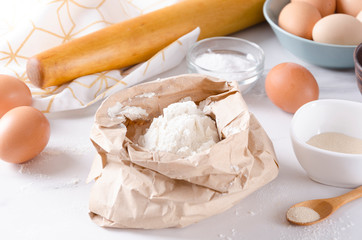 Closeup of bag with flour,dough roller, eggs, salt, yeast on the kitchen table.Fresh baking in the morning
