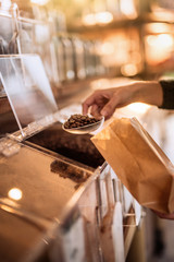  seller's hands filling a coffee bag from a bulk dispenser