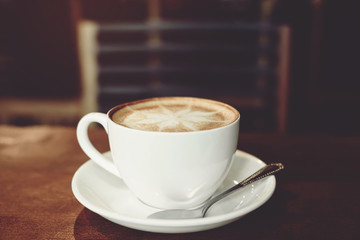 hot coffee cup latte art with spoon Serve ready to drink in cafe on wooden table coffee shop.  Leave copy space empty to write the side text. soft focus.