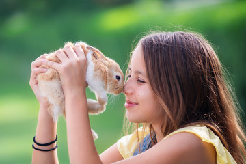 Young girl playing with little rabbit