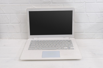 White laptop on the table and white wall behind