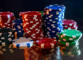 Colorful poker chips on reflecting surface close up