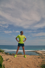 Sportsman stretching on a tropical exotic cliff near the ocean.