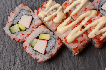 Uramaki sushi rolls with shrimp, cucumber topped with sauce and  caviar