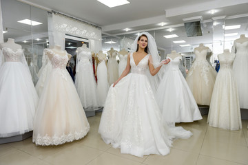 Naklejka premium Attractive young woman wearing wedding dress in bridal shop