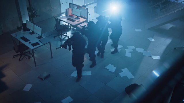 Masked Team of Armed SWAT Police Officers Slowly Move in a Hall of a Dark Seized Office Building with Desks and Computers. Soldiers with Rifles, Flashlights Surveil and Cover Surroundings. Above View.