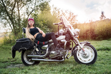 Fototapeta na wymiar A beautiful blonde woman sitting on a motorcycle