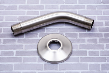 Brushed Nickel Metal Shower Arm and Flange isolated on brick wall background.