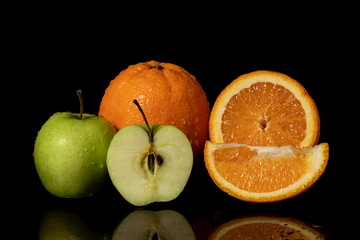 Apples and oranges fruits with drops and splashes of water on a black background