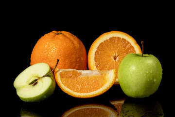 Apples and oranges fruits with drops and splashes of water on a black background