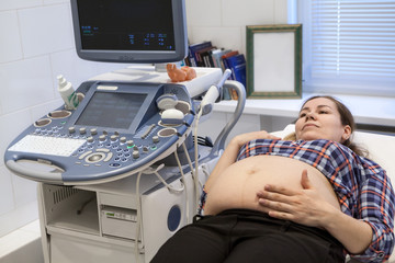 Caucasian pregnant female visiting women's doctor in maternity center for doing ultrasound scan
