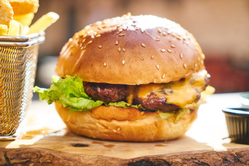 Cheeseburger with french fries on the wooden table