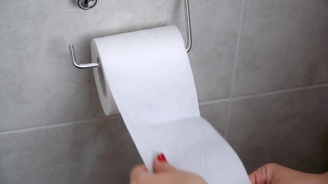 Young woman takes toilet paper in hand. Hand taking sheets of paper from a toilet roll