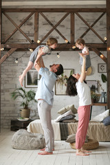 Fototapeta na wymiar mom and dad hold children in air, casual home