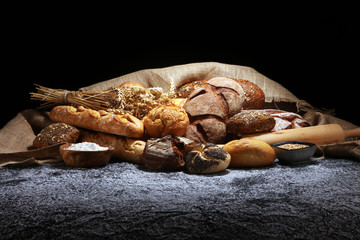 Assortment of baked bread and bread rolls on rustic grey bakery table background
