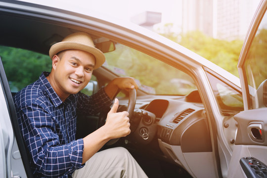 Portrait of happy smiling Young asian man traveler on the road showing thumbs up while driving in his car.