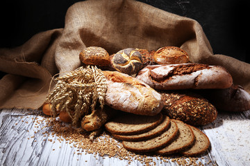 Assortment of baked bread and bread rolls on rustic white bakery table background