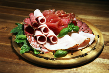 Food tray with delicious salami, pieces of sliced ham, sausages,salad and vegetable. Meat platter with selection