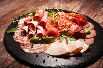 Food tray with delicious salami, pieces of sliced ham, sausages,salad and vegetable. Meat platter with selection