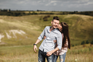 Young couple outdoor portrait. Beautiful pretty girl kissing handsome boy. Sensual photo.