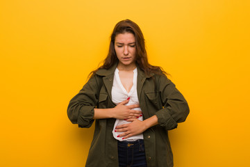 Young european woman isolated over yellow background sick, suffering from stomachache, painful disease concept.